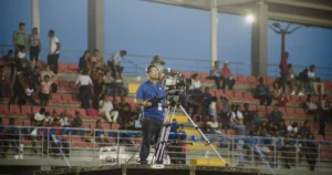 Operador de cámara retransmitiendo un evento en directo desde un recinto al aire libre lleno de público