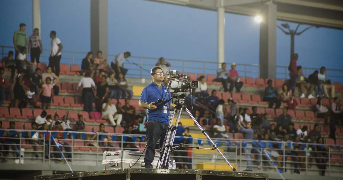 Operador de cámara retransmitiendo un evento en directo desde un recinto al aire libre lleno de público